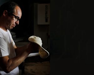 Le champion de France de pizza, Gregory Edel, prépare sa pâte à pizza avec passion et expertise. Ses mains habiles travaillent la pâte avec précision, promettant une pizza délicieuse et authentique.