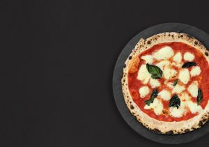Une pizza napolitaine classique, garnie de tomates fraîches, de mozzarella fondante et de basilic frais, sort d'un four à bois traditionnel. La pâte est dorée et croustillante, et les ingrédients sont de qualité supérieure.